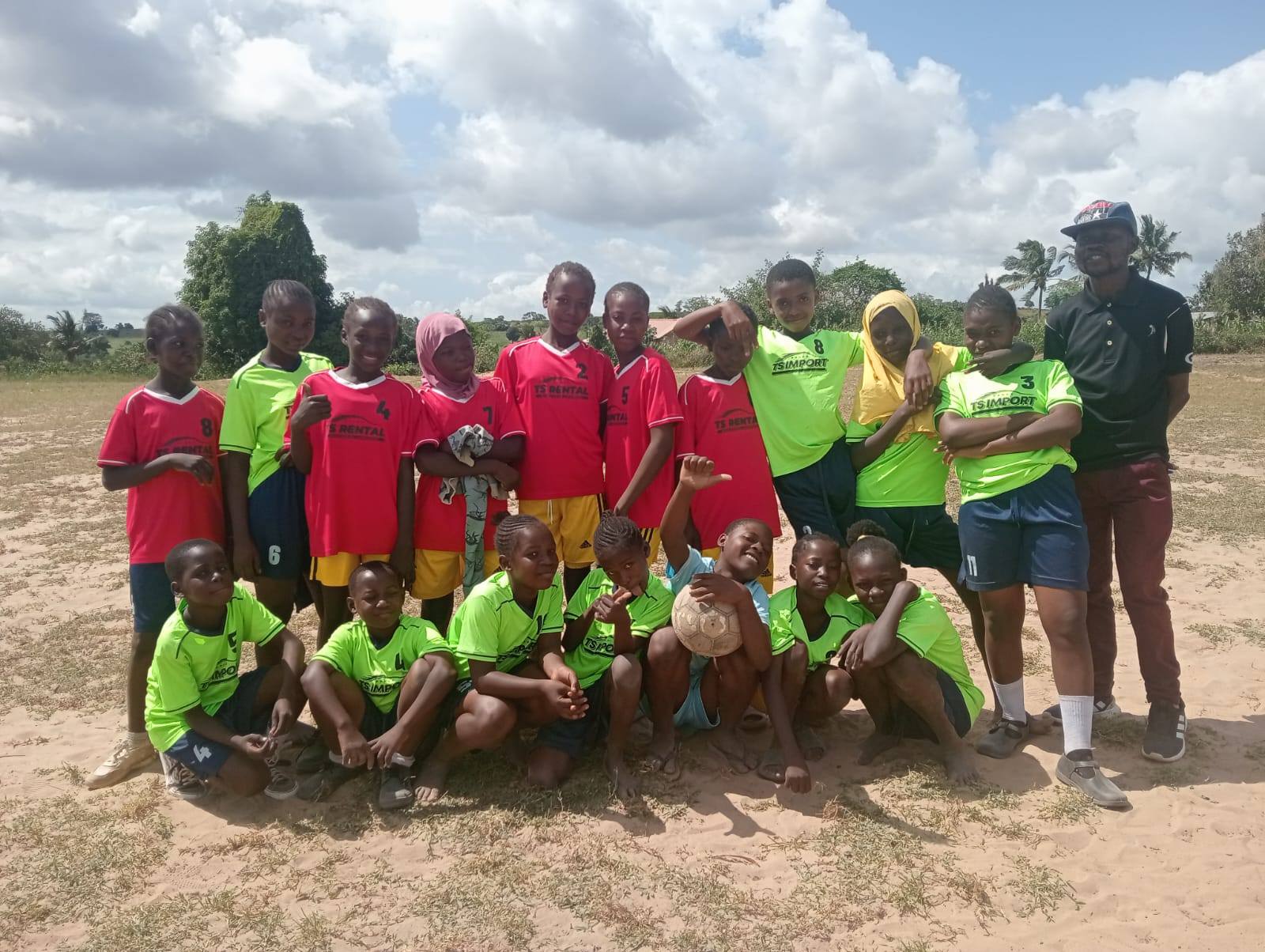Children in football uniforms with their coach